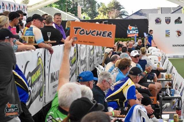 A spectator holding a Toucher sign above the crowd beside the green