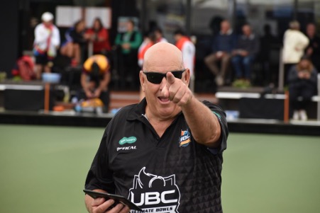 A UBC volunteer pointing towards the camera beside the green