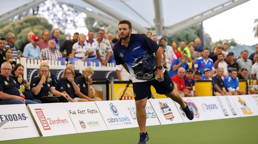 Bowler following through on a delivery in front of a packed crowd