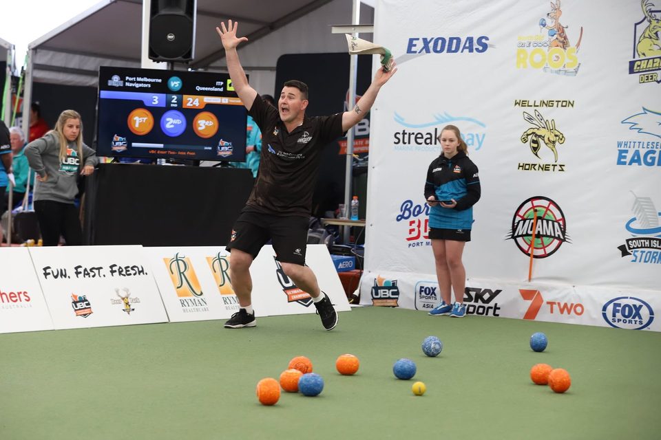 Player leaping with arms raised beside the rink after a winning bowl