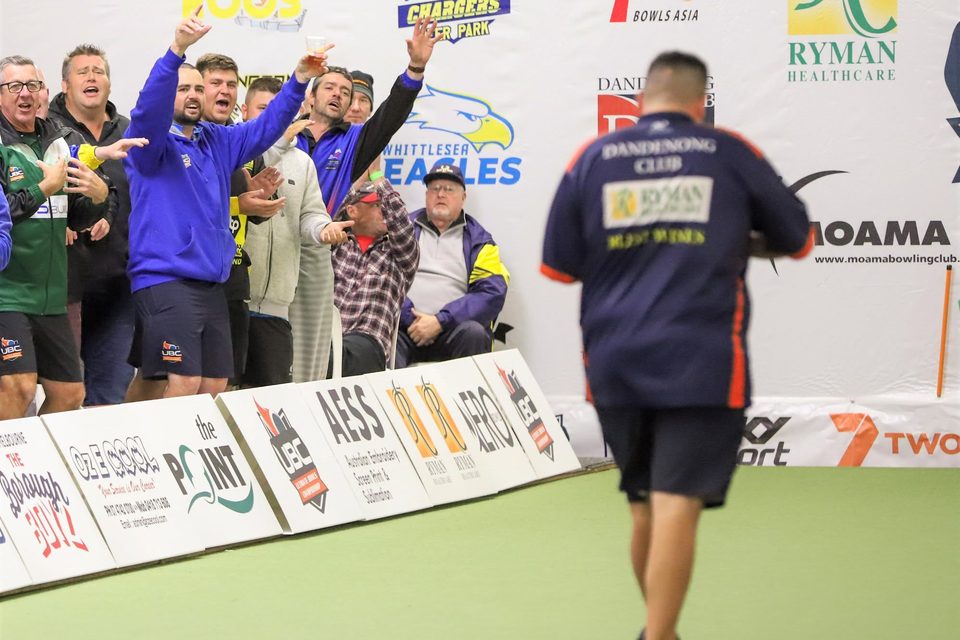 Supporters cheering from behind the rink banners as a Dandenong Club player walks back