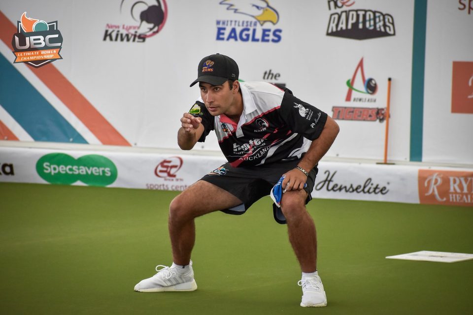Auckland player crouching low to watch his bowl run