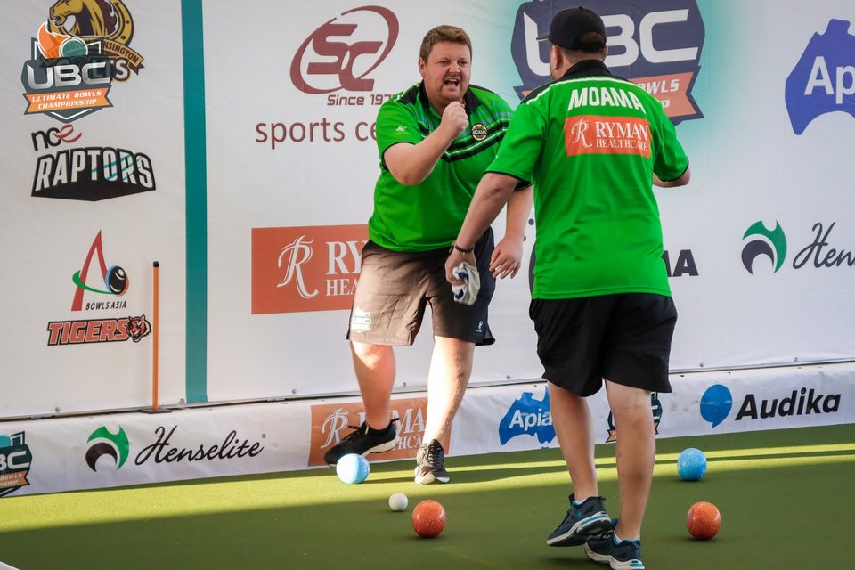 Player in a green Moama shirt pumping his fist as a teammate turns away