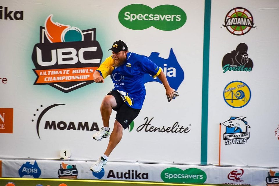 Player kicking up a heel in celebration in front of the UBC sponsor wall
