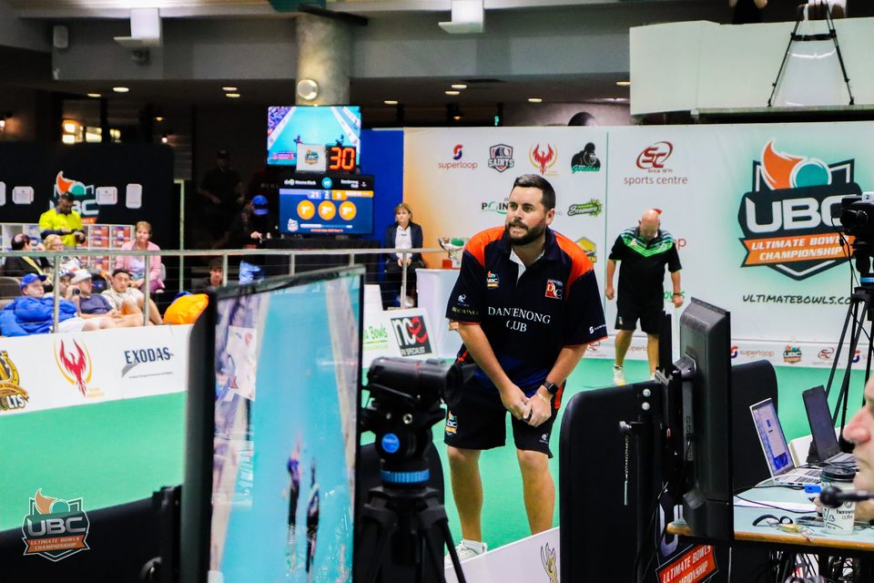 Dandenong Club player watching play beside the broadcast camera and monitors